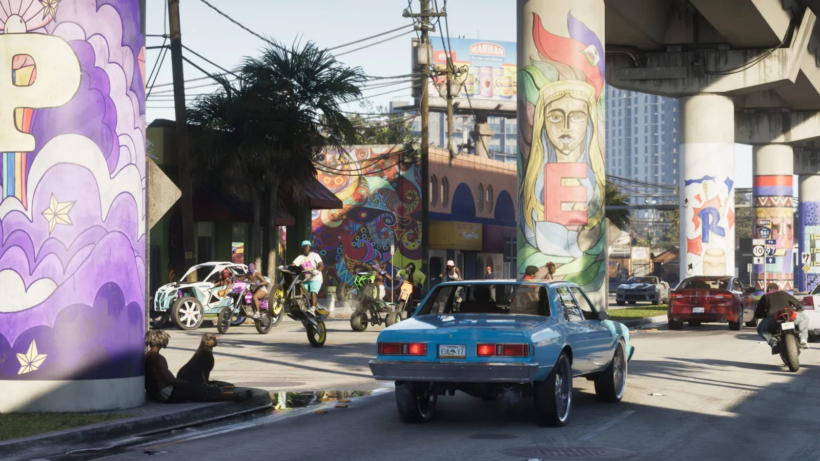 A classic blue muscle car on a mural-covered Vice City street in GTA 6, bikes and pedestrians around